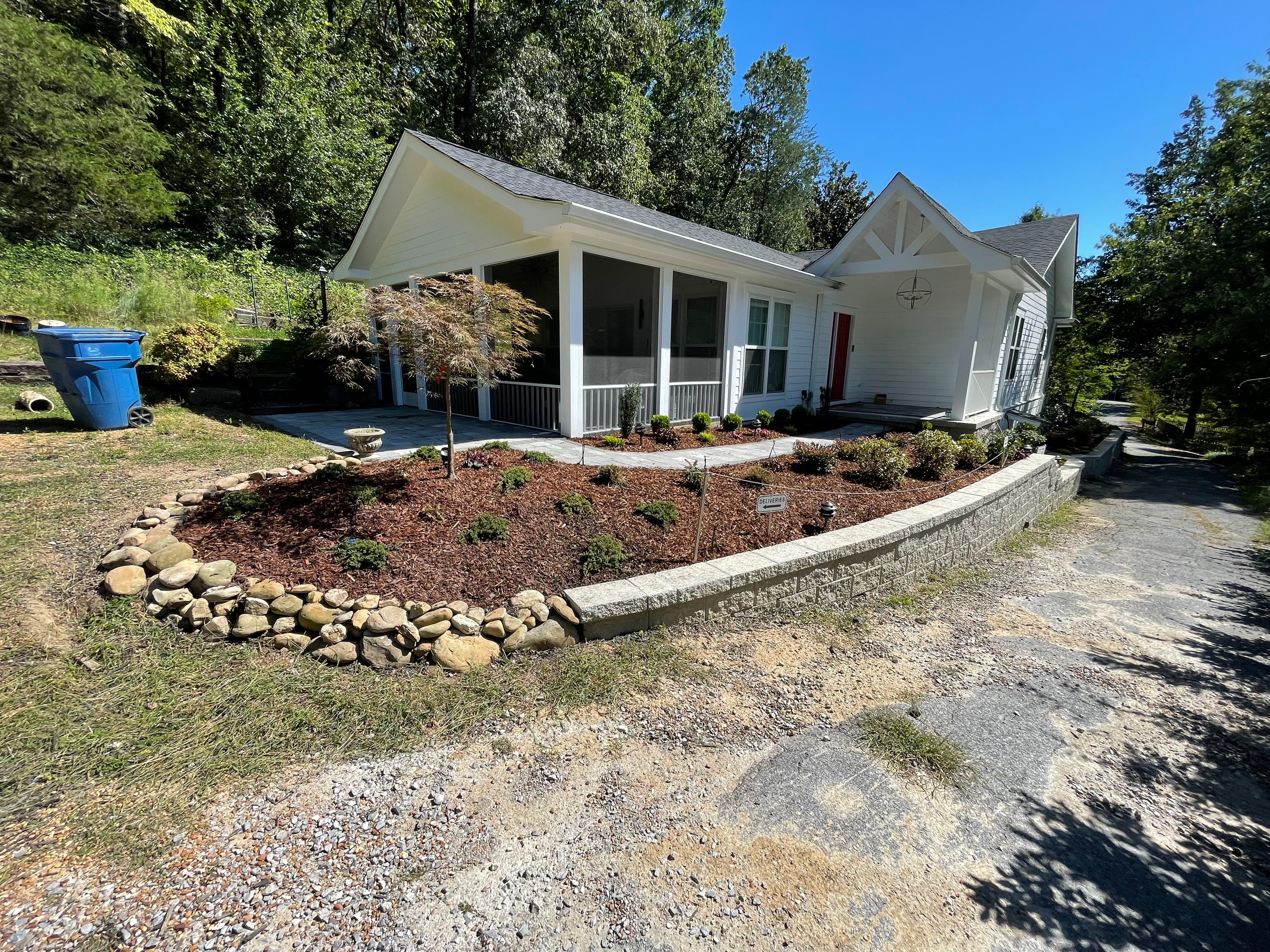 White cottage with landscaped garden bed and retaining wall