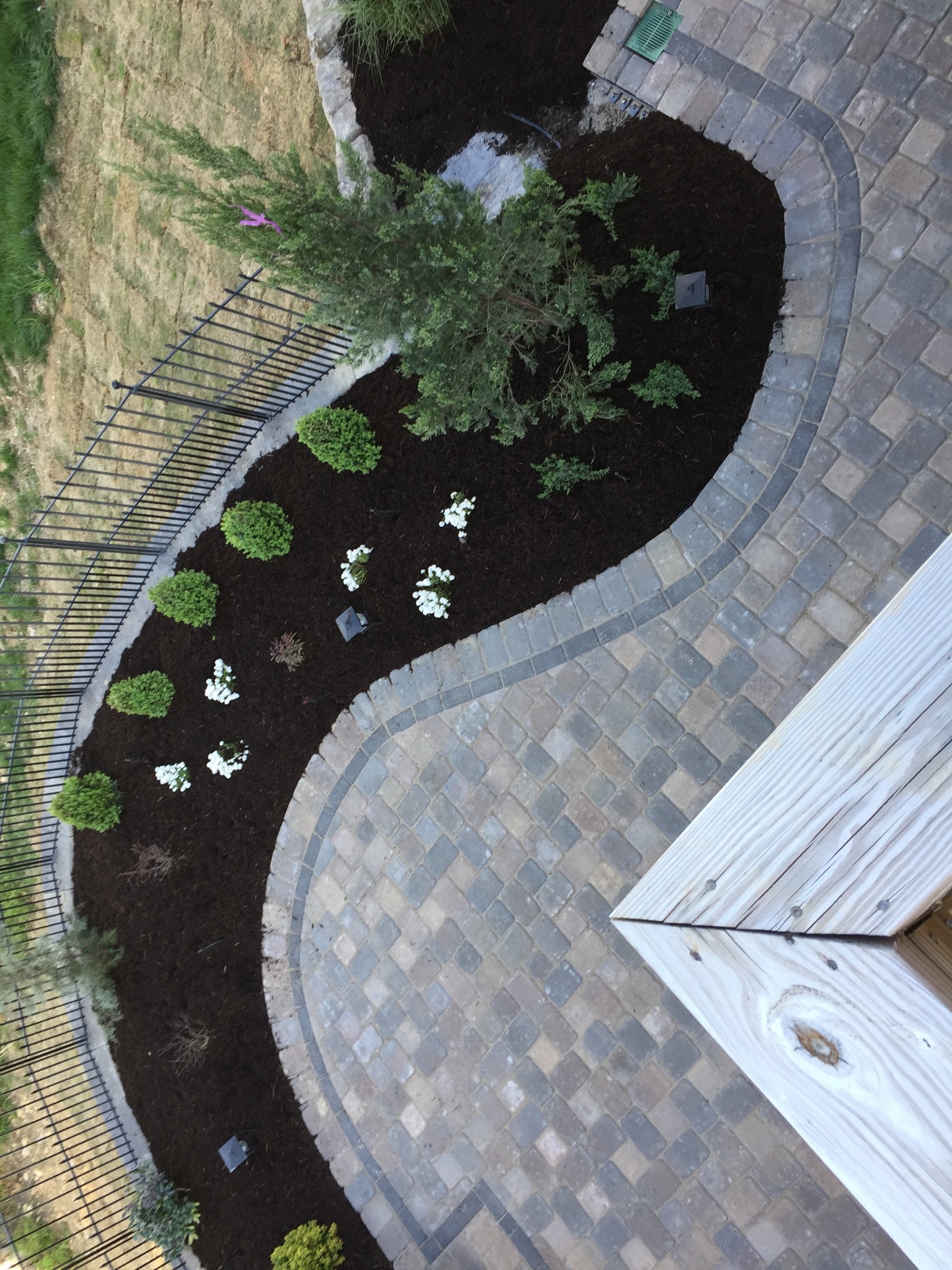 Aerial view of curved paver patio with garden bed